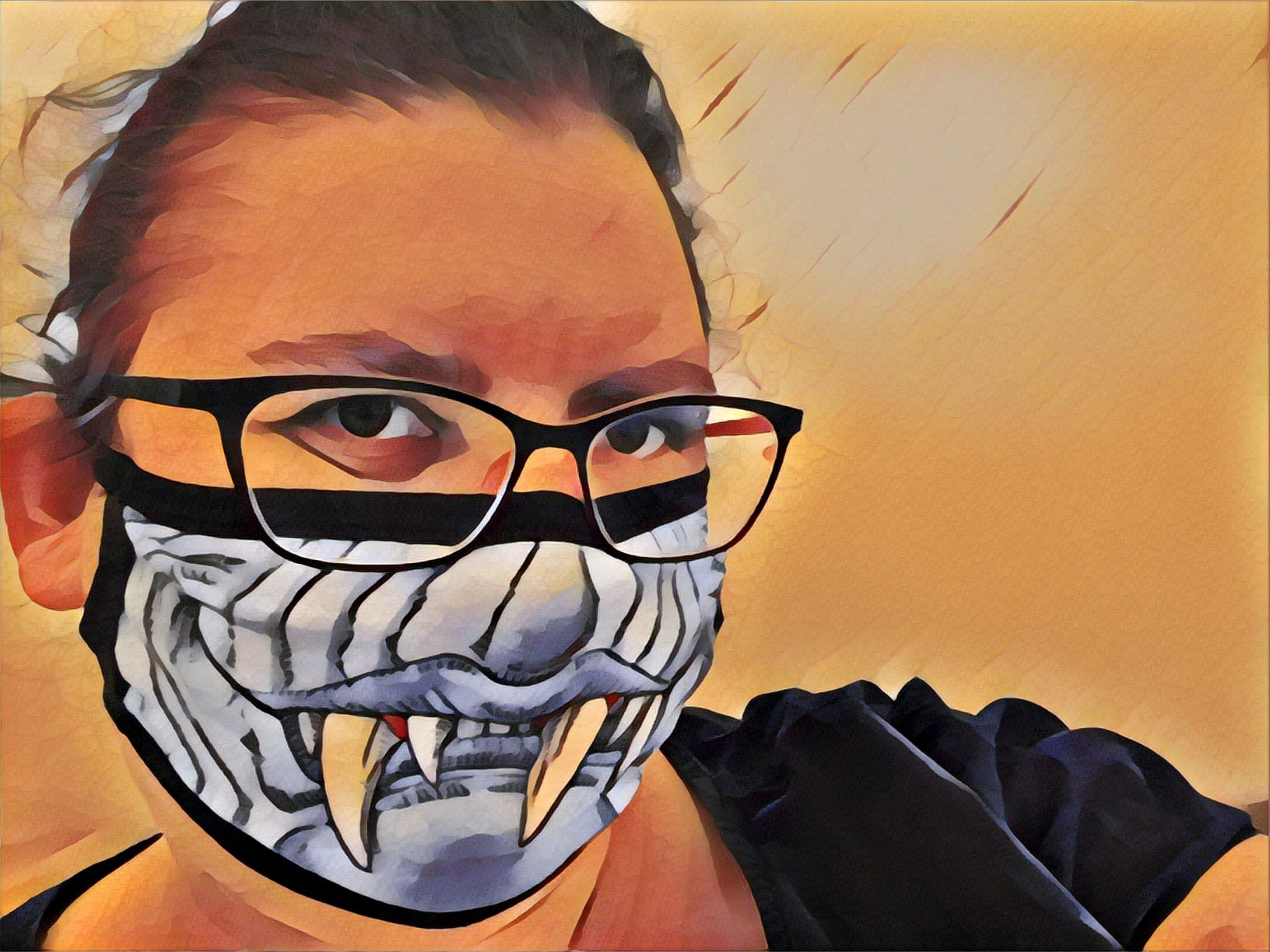 Picture of the head of a woman with hair tied back, wearing glasses and a mask with an ogre face on it.
