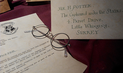 illustration with the hogwarts letter for Mr H Potter and a pair of rounded glasses